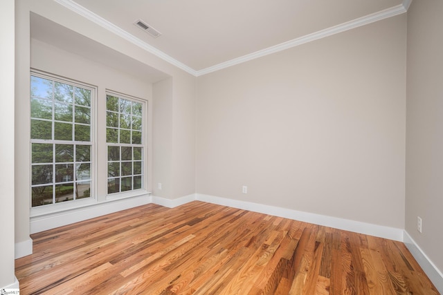 empty room featuring light wood-style flooring, crown molding, baseboards, and visible vents