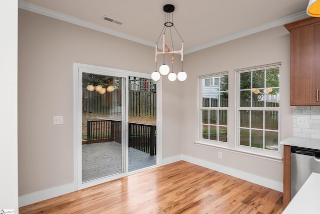 unfurnished dining area with light wood-style floors, visible vents, baseboards, and crown molding