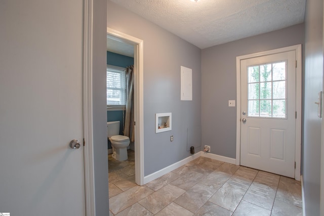 clothes washing area with baseboards, laundry area, a textured ceiling, and hookup for a washing machine