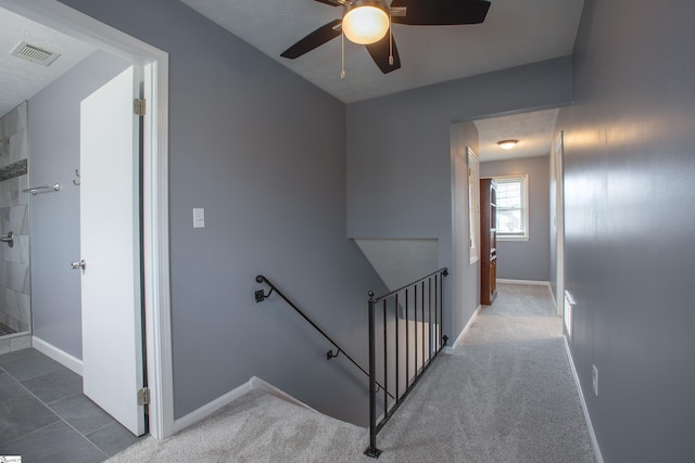 staircase featuring visible vents, baseboards, a ceiling fan, and carpet