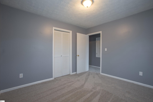 unfurnished bedroom with carpet, a closet, baseboards, and a textured ceiling