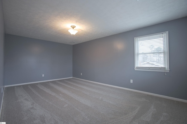 carpeted empty room with a textured ceiling and baseboards