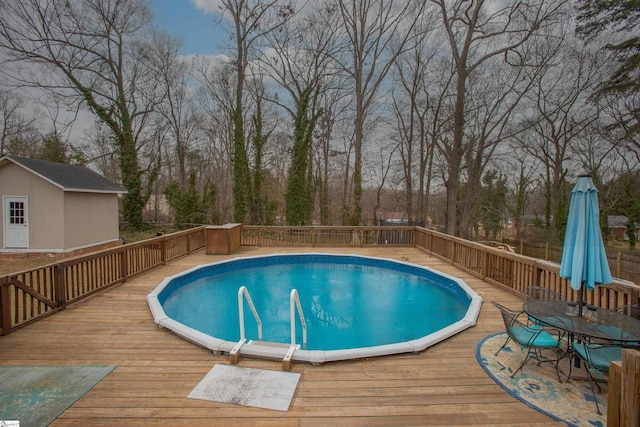 view of pool with outdoor dining space, a fenced in pool, a deck, and an outdoor structure