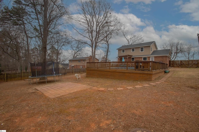 view of yard with a patio area, a fenced backyard, a trampoline, and a deck