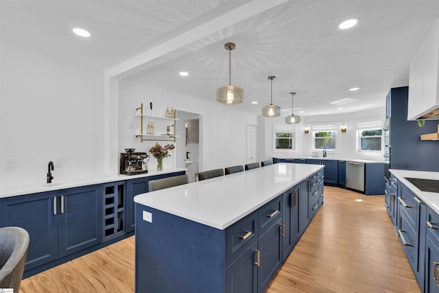 kitchen with light wood-style flooring, light countertops, a kitchen island, stainless steel dishwasher, and blue cabinets
