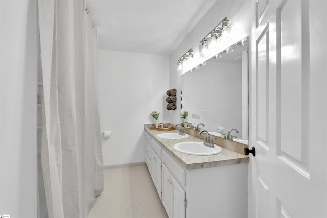 full bath featuring double vanity, a sink, and baseboards