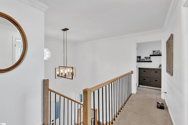 hallway with carpet, ornamental molding, an upstairs landing, baseboards, and a notable chandelier