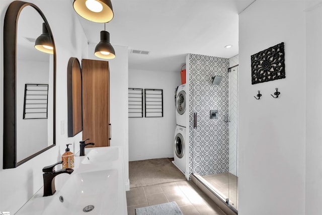 full bath with a sink, visible vents, stacked washer and clothes dryer, and a stall shower