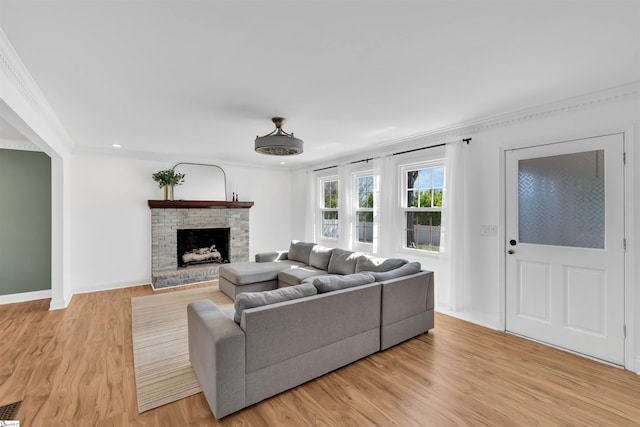 living room with ornamental molding, light wood-style flooring, baseboards, and a fireplace