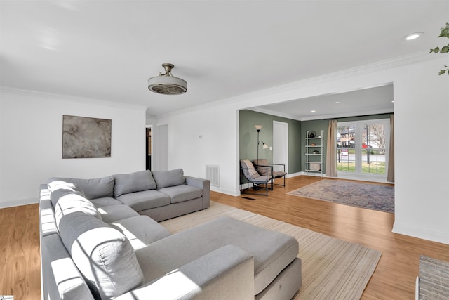 living room with visible vents, ornamental molding, baseboards, and wood finished floors