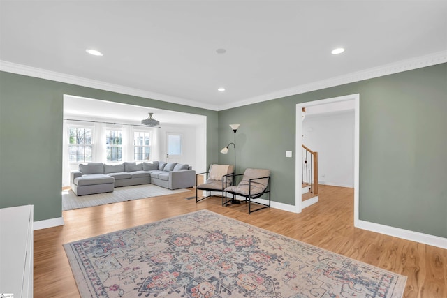 living area with crown molding, wood finished floors, baseboards, and stairs