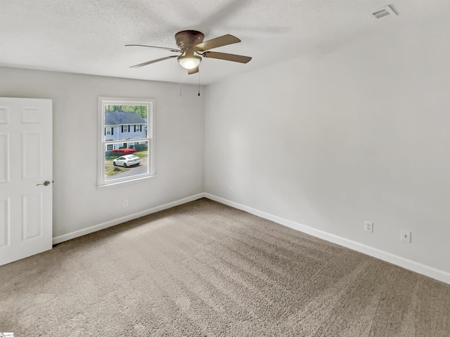 carpeted empty room with visible vents, ceiling fan, baseboards, and a textured ceiling