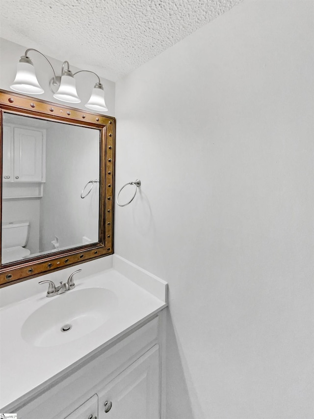 bathroom with toilet, a textured ceiling, and vanity