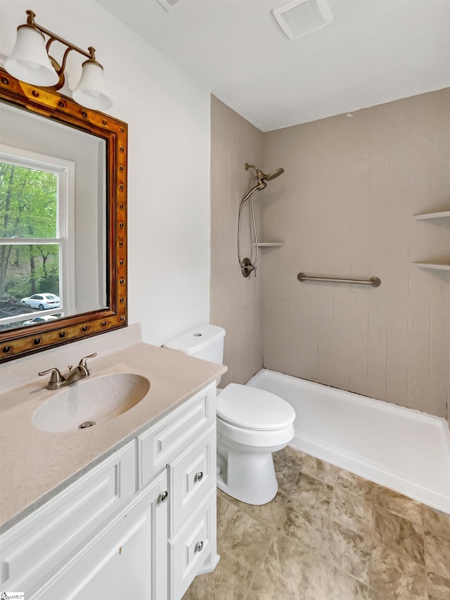 full bath featuring visible vents, toilet, tiled shower, and vanity