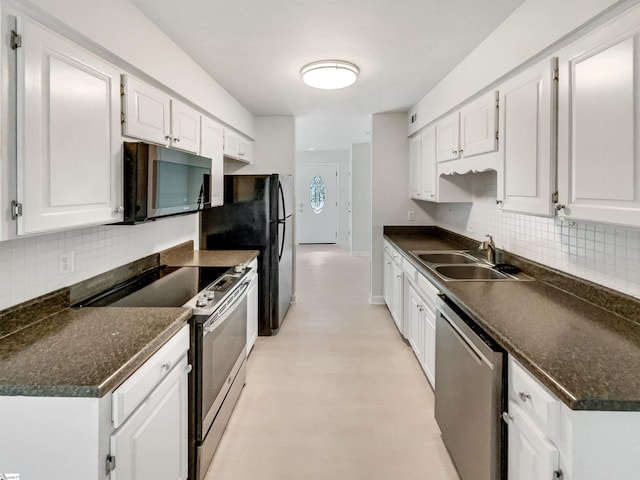 kitchen featuring tasteful backsplash, dark countertops, white cabinets, stainless steel appliances, and a sink