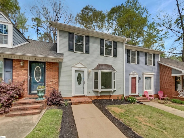 colonial home with brick siding and a shingled roof