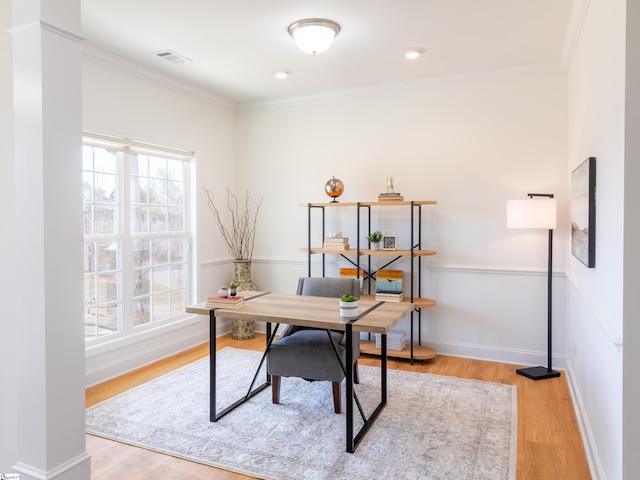 office space featuring baseboards, crown molding, light wood-style floors, visible vents, and decorative columns