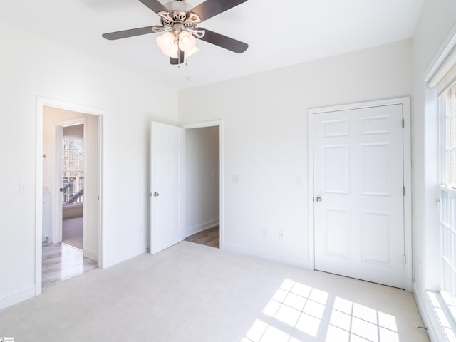 unfurnished bedroom with light carpet, baseboards, and a ceiling fan