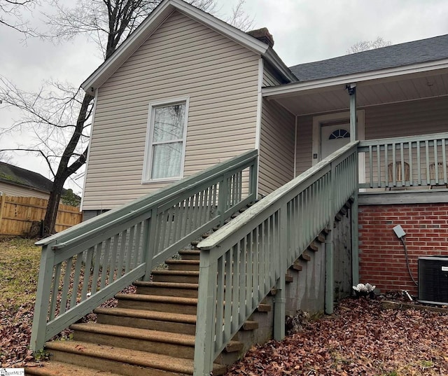doorway to property with central AC and fence