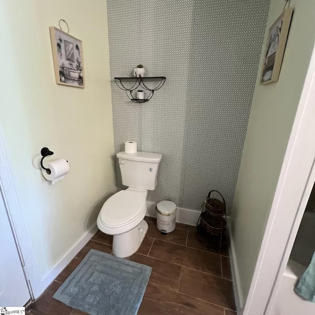 bathroom with toilet, baseboards, and wood finish floors