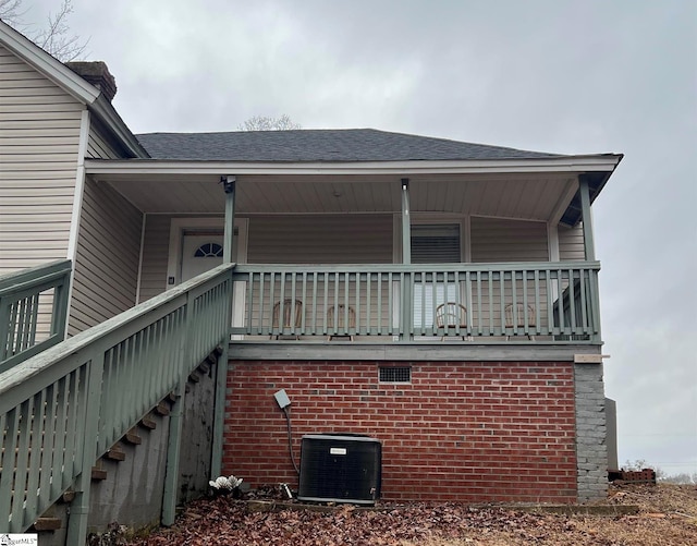 view of side of property with central AC, brick siding, and covered porch