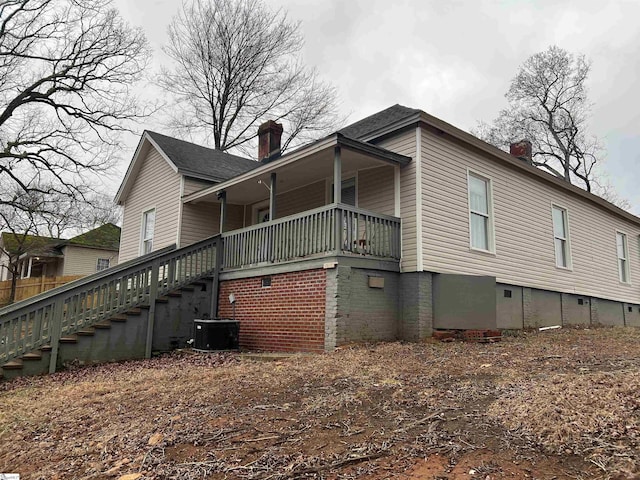 view of side of home with stairs, central air condition unit, and a chimney