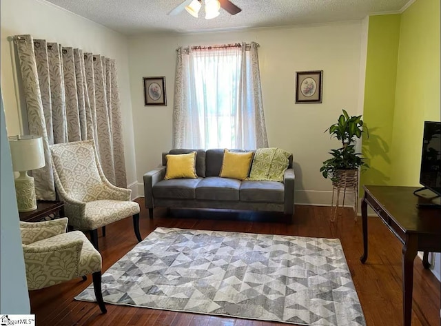 living room featuring baseboards, a ceiling fan, wood finished floors, and a textured ceiling