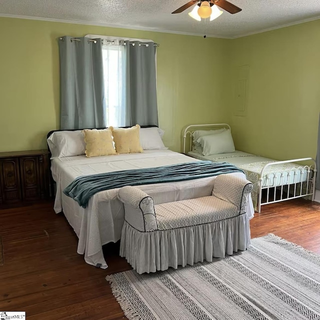 bedroom with a textured ceiling, ornamental molding, and wood finished floors