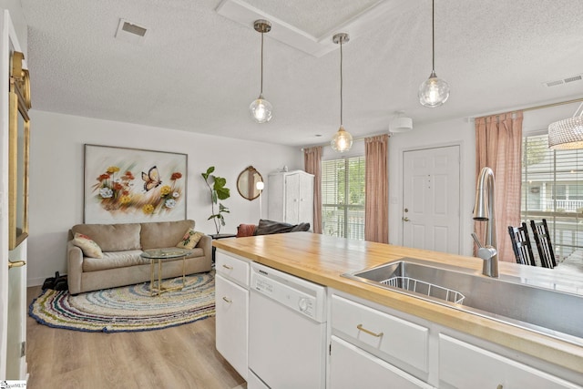 kitchen with light wood-type flooring, white cabinetry, visible vents, dishwasher, and a sink