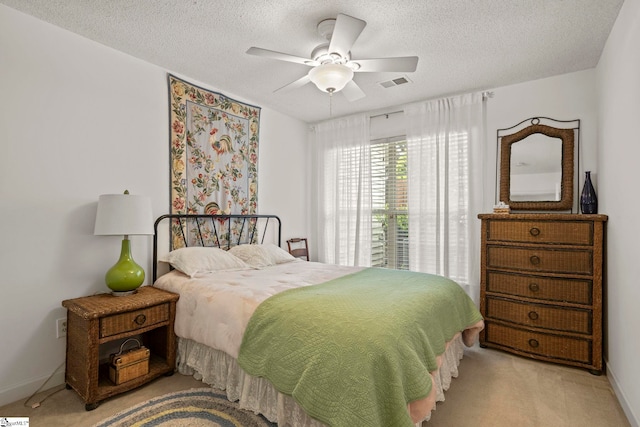 bedroom featuring baseboards, a textured ceiling, a ceiling fan, visible vents, and light colored carpet