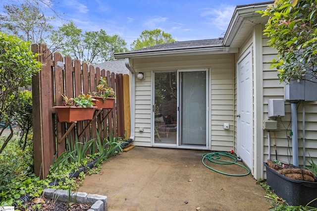 view of exterior entry featuring a patio and fence