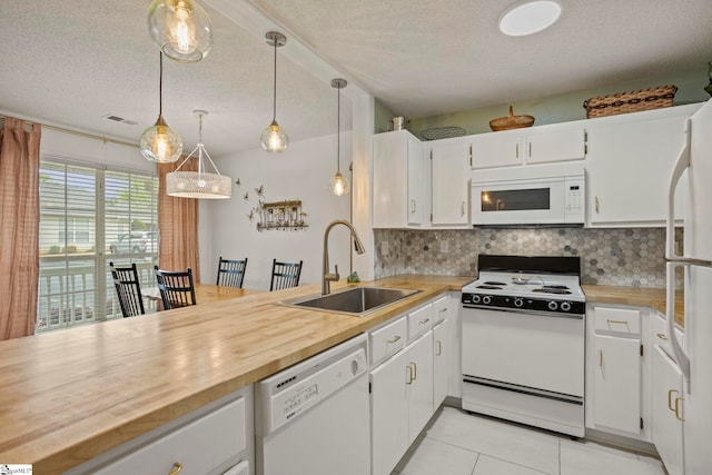 kitchen with tasteful backsplash, visible vents, a sink, white appliances, and butcher block counters