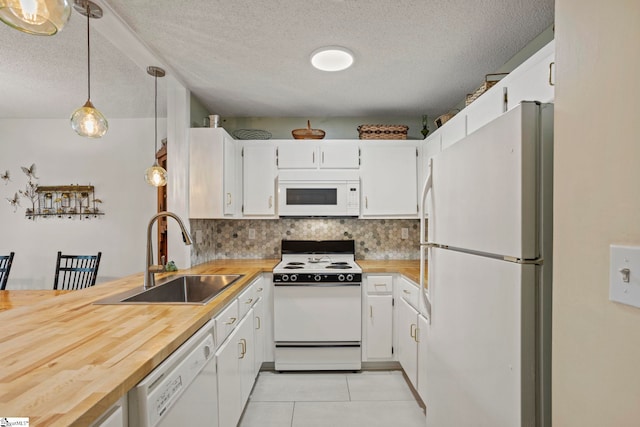 kitchen featuring white appliances, tasteful backsplash, light tile patterned flooring, a sink, and butcher block countertops