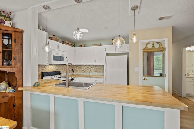 kitchen featuring tasteful backsplash, visible vents, a sink, white appliances, and a peninsula