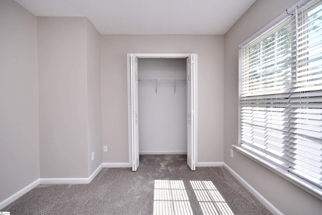 unfurnished bedroom with a closet, carpet flooring, and baseboards