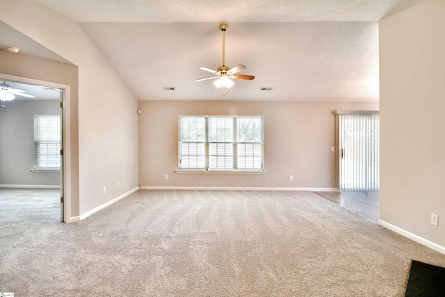 empty room featuring a wealth of natural light, carpet, vaulted ceiling, and a ceiling fan