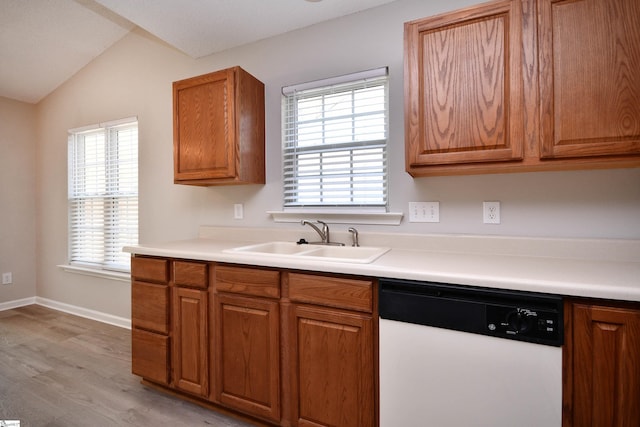kitchen with vaulted ceiling, light countertops, a sink, white dishwasher, and brown cabinets