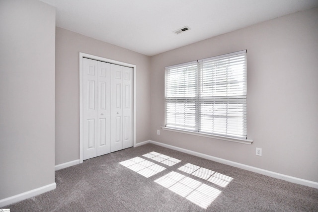 unfurnished bedroom featuring a closet, carpet, visible vents, and baseboards