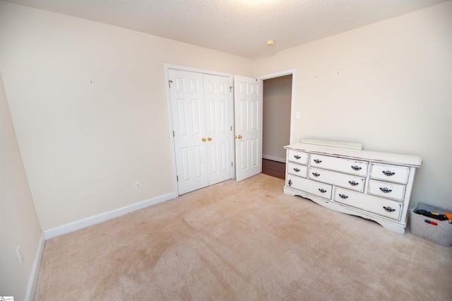 unfurnished bedroom with carpet flooring, a closet, baseboards, and a textured ceiling