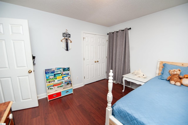 bedroom with a closet, a textured ceiling, baseboards, and wood finished floors