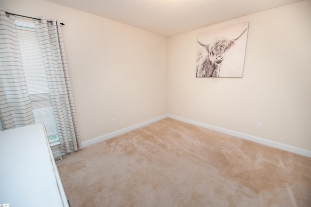 empty room featuring baseboards, carpet flooring, and a textured ceiling
