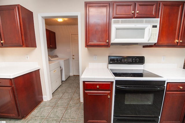 kitchen featuring washer and dryer, white microwave, dark brown cabinets, and electric range oven