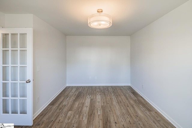 spare room with baseboards and wood finished floors