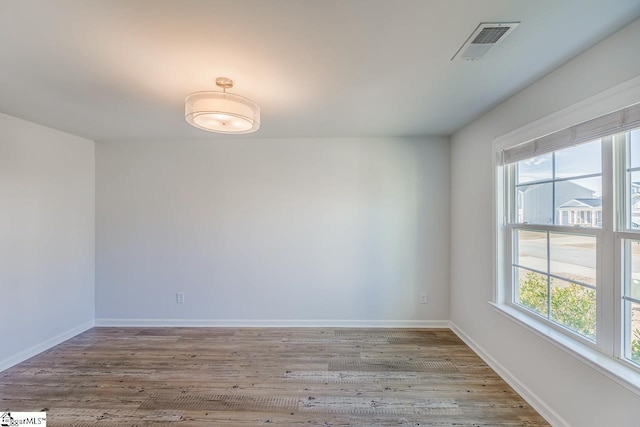 empty room with visible vents, wood finished floors, and a healthy amount of sunlight