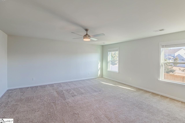 empty room featuring carpet flooring, baseboards, a ceiling fan, and visible vents