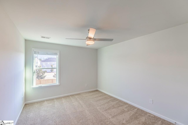 spare room with visible vents, light colored carpet, baseboards, and ceiling fan