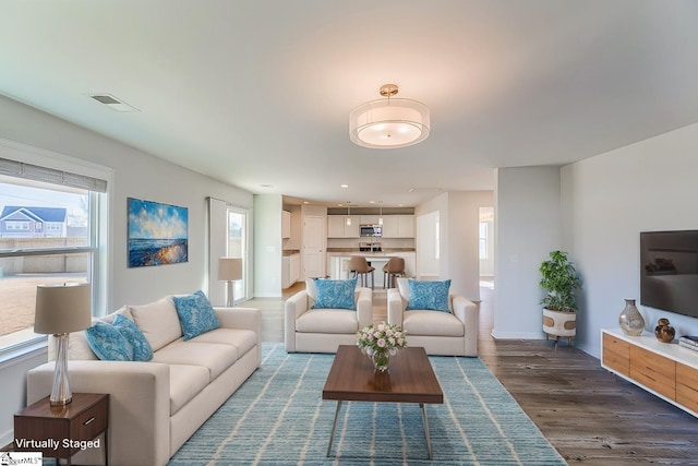 living area featuring wood finished floors, baseboards, and visible vents