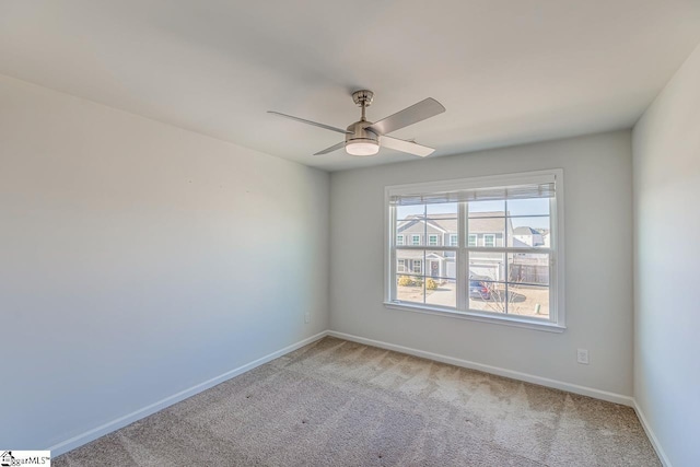 carpeted empty room featuring baseboards and a ceiling fan