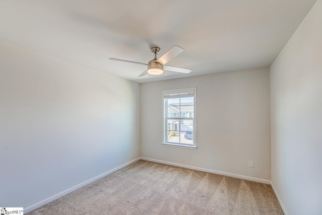 spare room with baseboards, ceiling fan, and light carpet