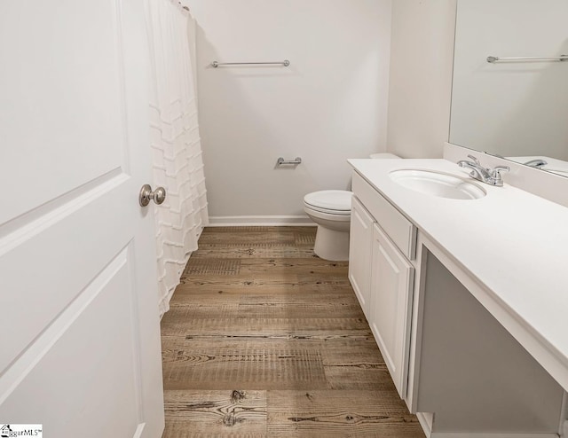 bathroom featuring baseboards, curtained shower, toilet, vanity, and wood finished floors